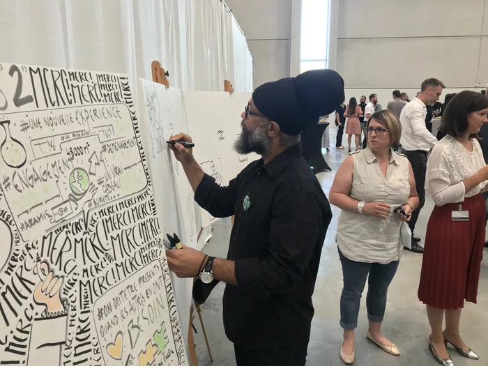 Gros plan sur Philippe Rilos en train de dessiner, observé par des participants