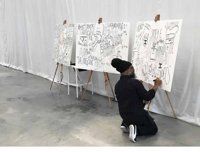 Philippe Rilos agenouillé devant trois panneaux de fresque terminés